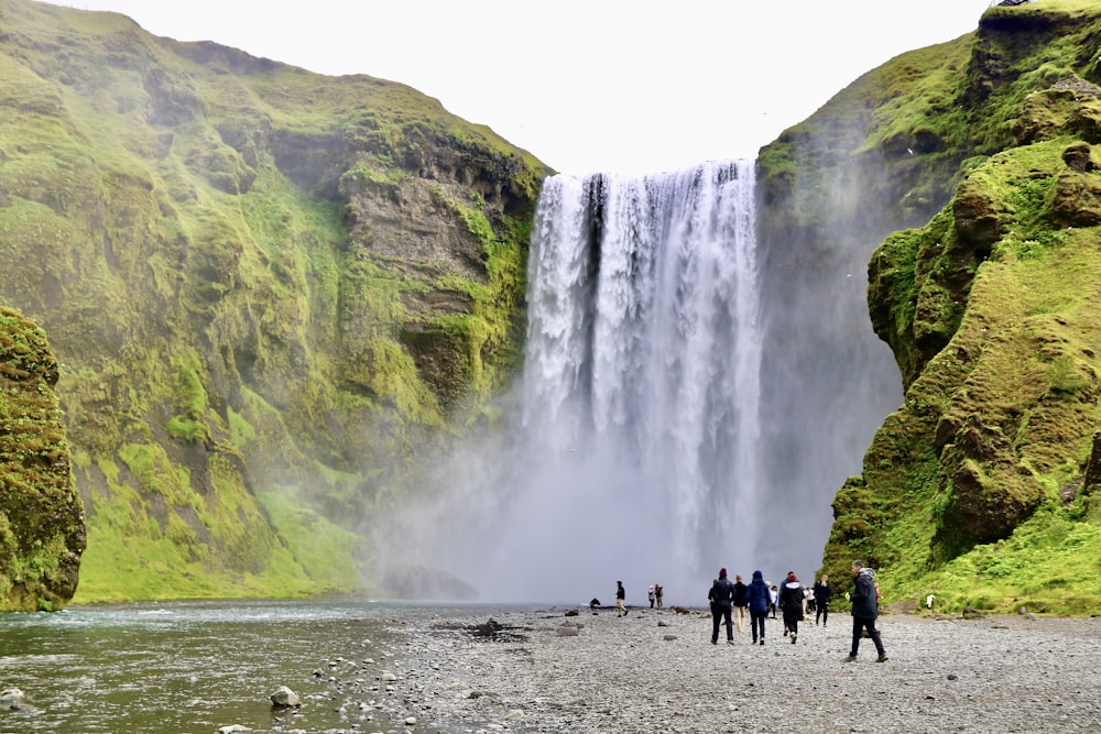 um grupo de pessoas em pé em frente a uma cachoeira