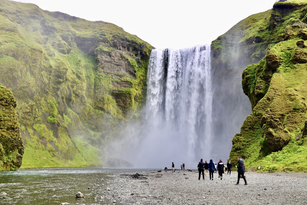 a group of people standing in front of a waterfall