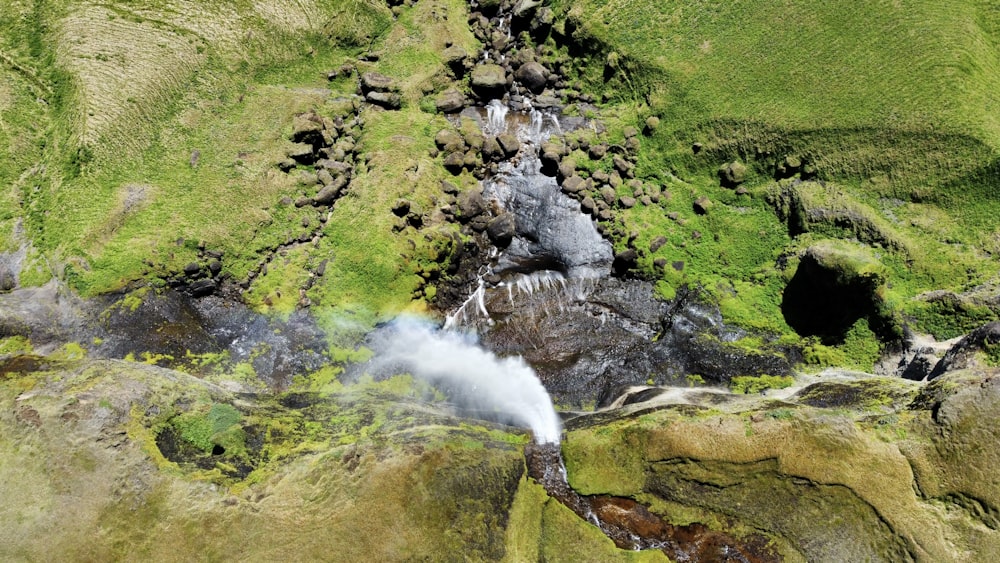 an aerial view of a stream running through a green mountain