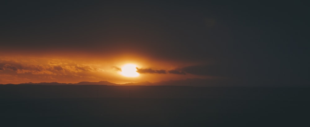 the sun is setting over a mountain range