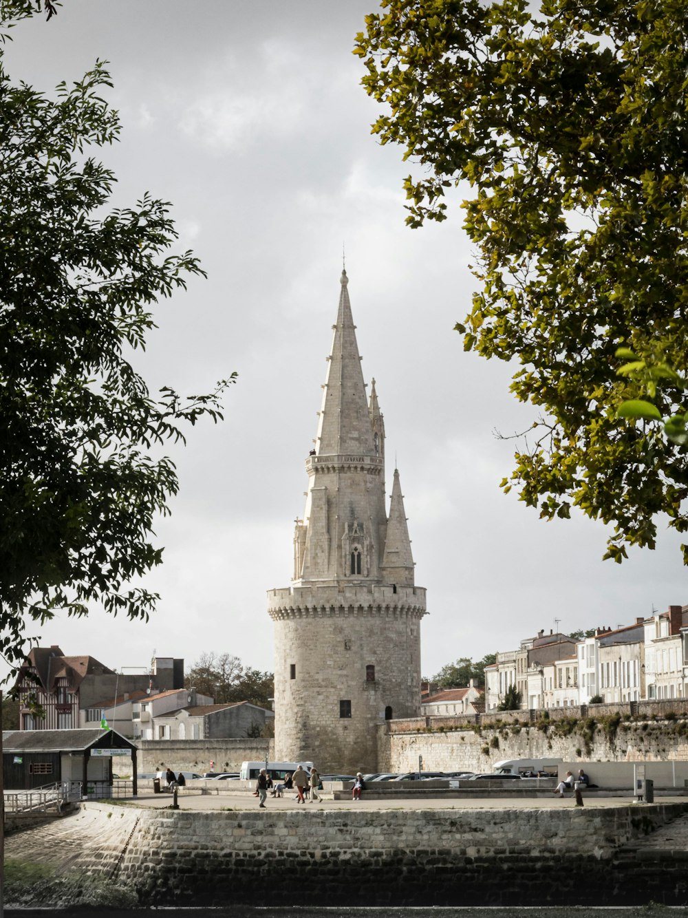 une haute tour assise à côté d’une rivière sous un ciel nuageux