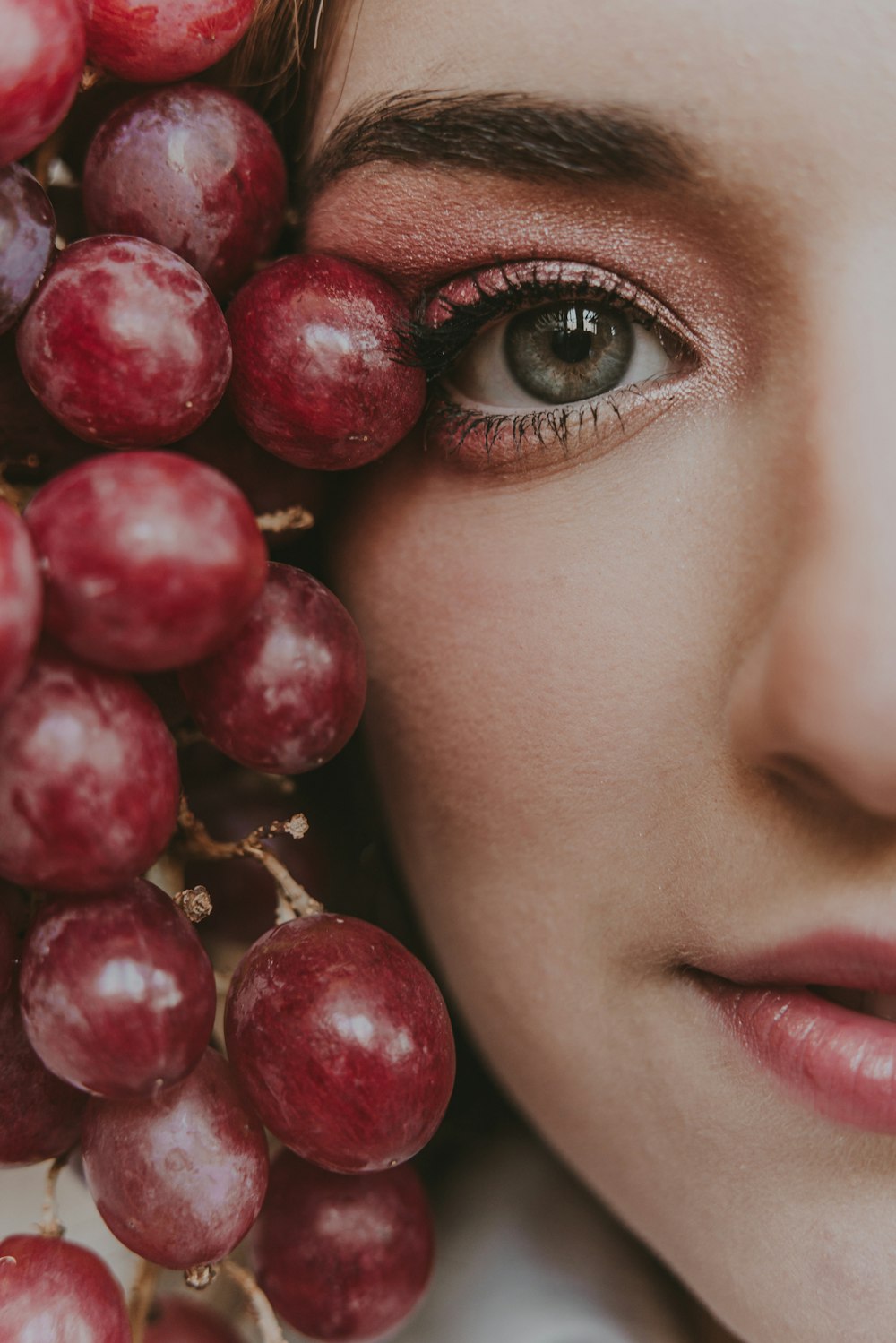 a close up of a woman with grapes on her face