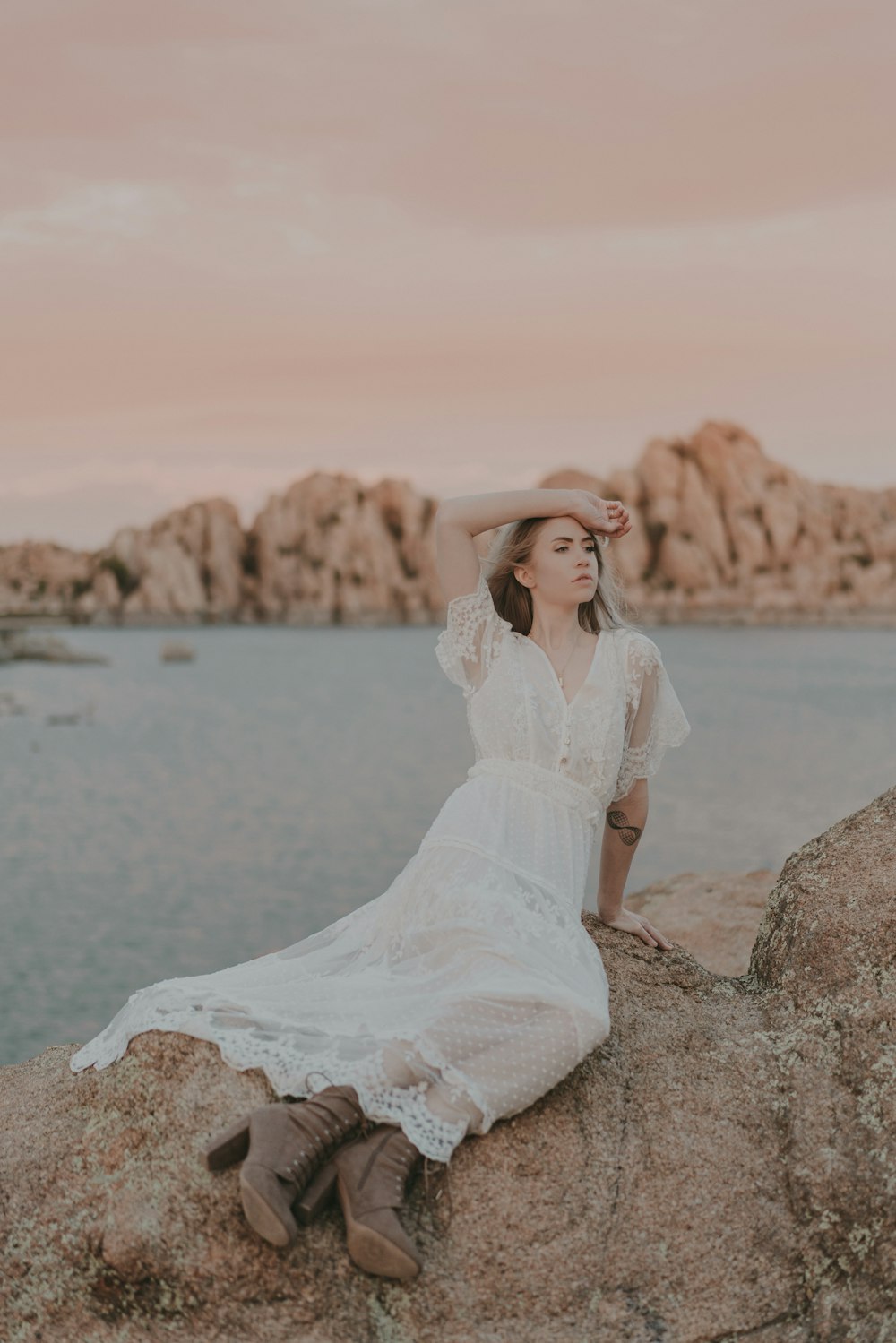 a woman sitting on top of a rock near the ocean