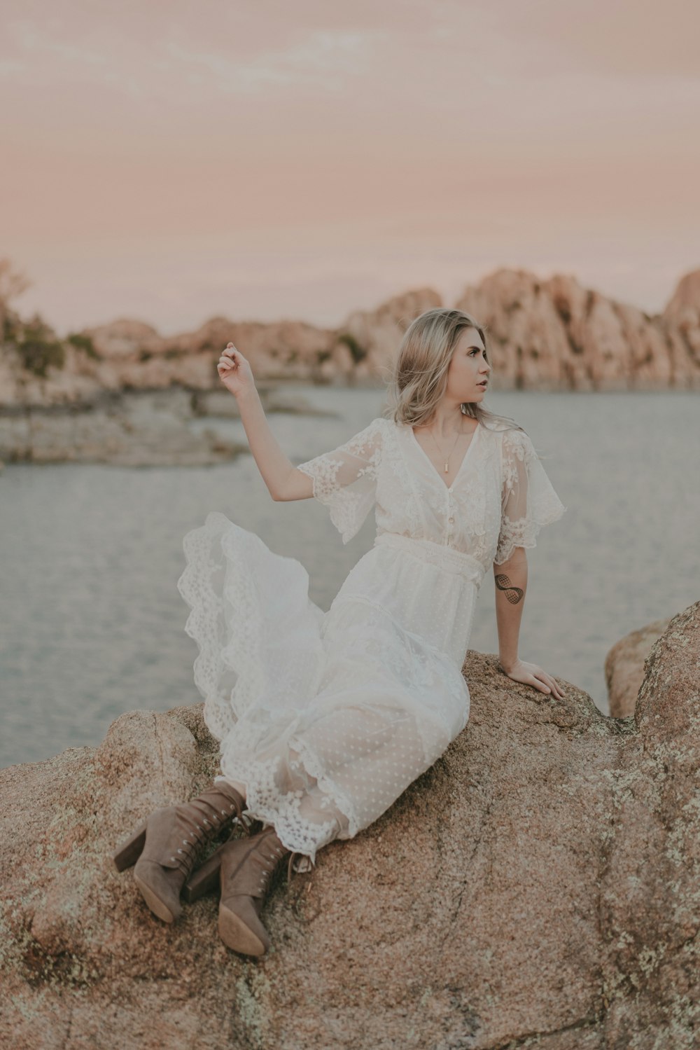 岩の上に座っている白いドレスを着た女性