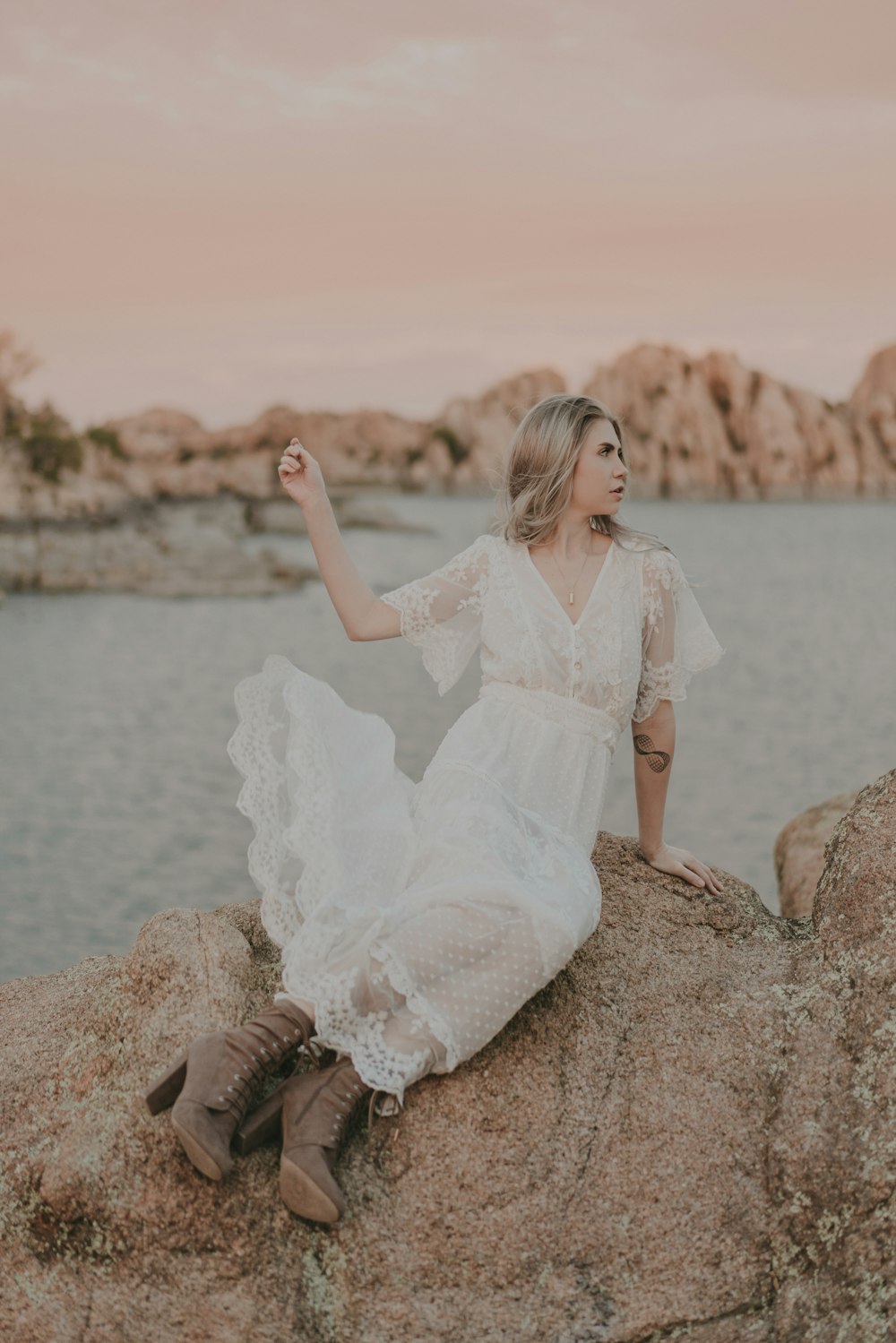 a woman in a white dress sitting on a rock