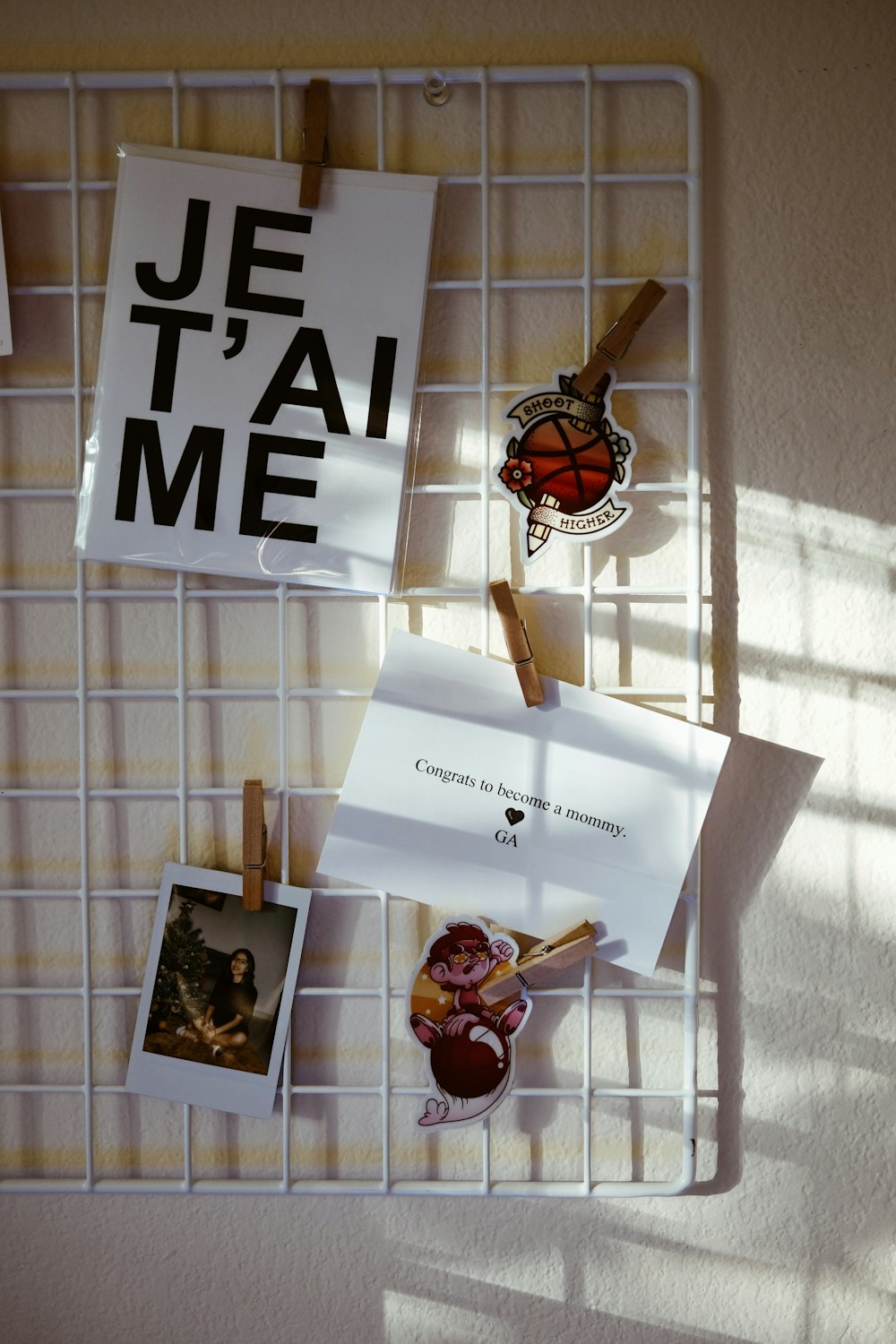a white wire rack holding photos and magnets