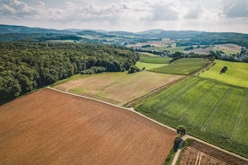 an aerial view of a large field with trees in the background