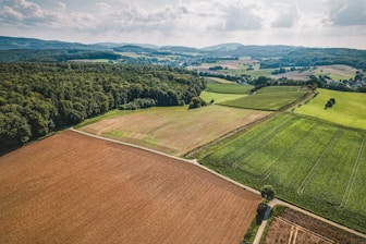 an aerial view of a large field with trees in the background