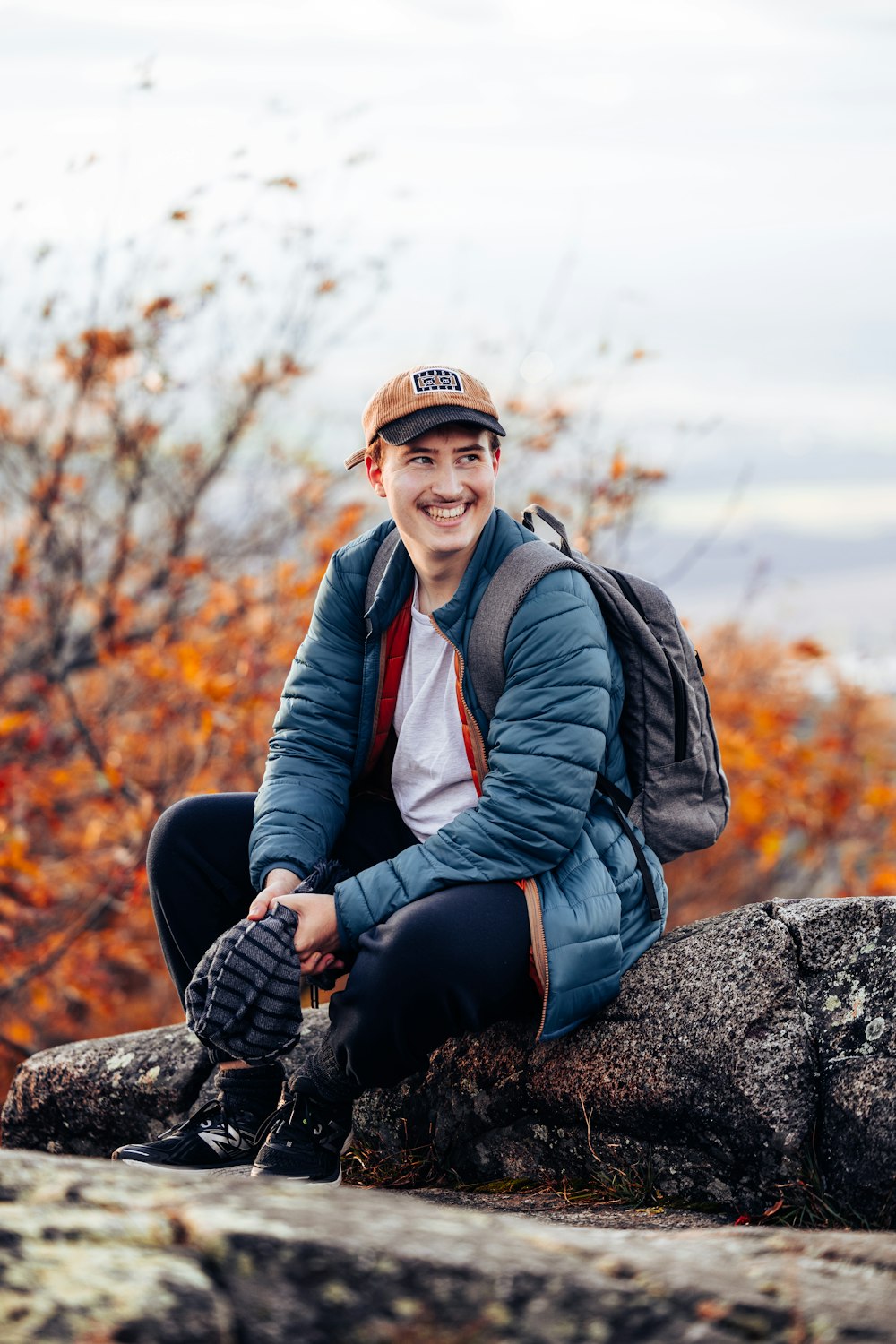 a person sitting on a rock with a backpack