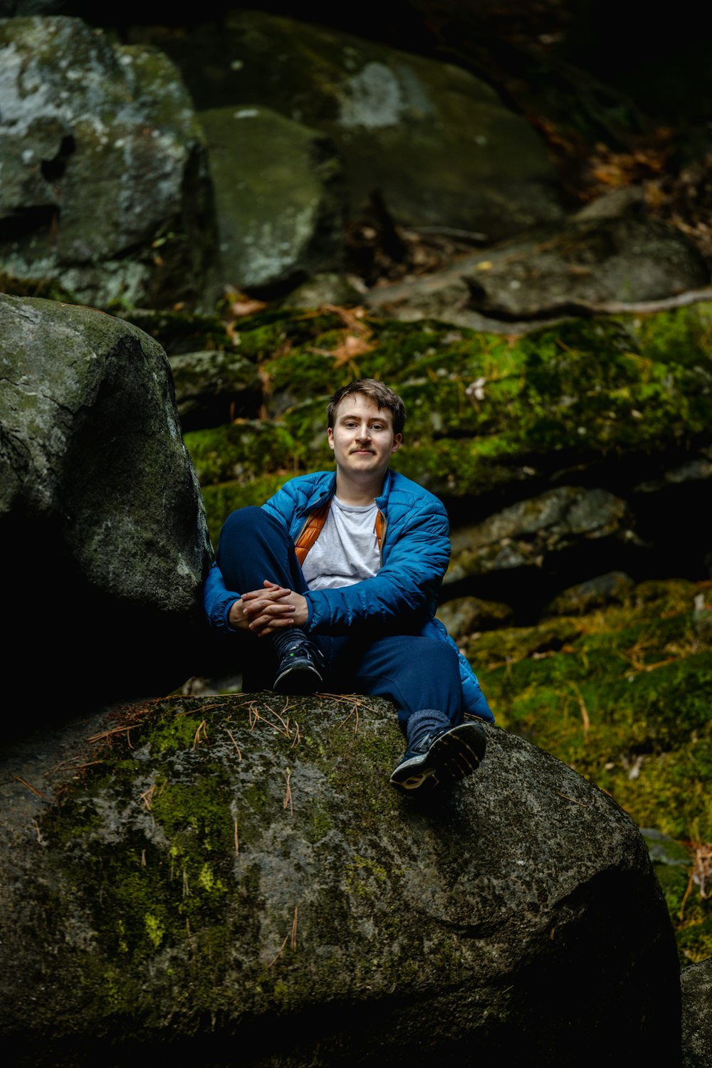 a man sitting on top of a large rock