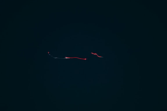 A sleek, transparent contact form overlaying a blurred cinematic background with red accents.