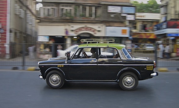 a black car driving down a street next to tall buildings