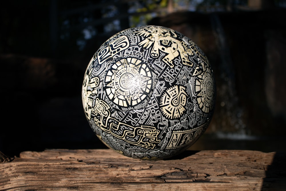 a black and white ball sitting on top of a piece of wood