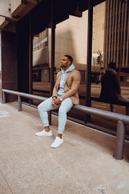 a man sitting on a rail in front of a building