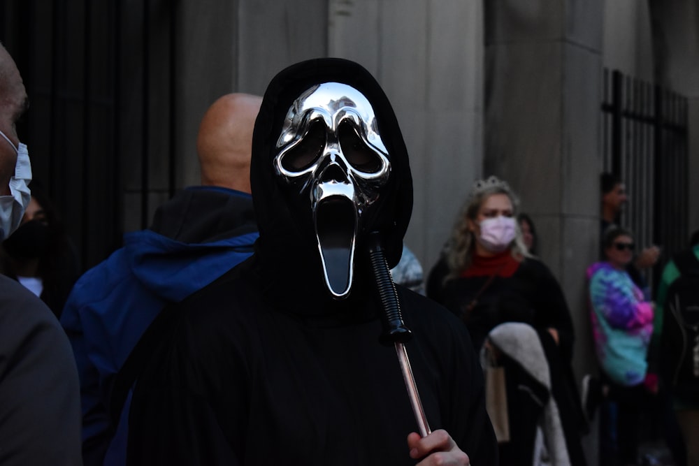 a person wearing a mask and holding a stick
