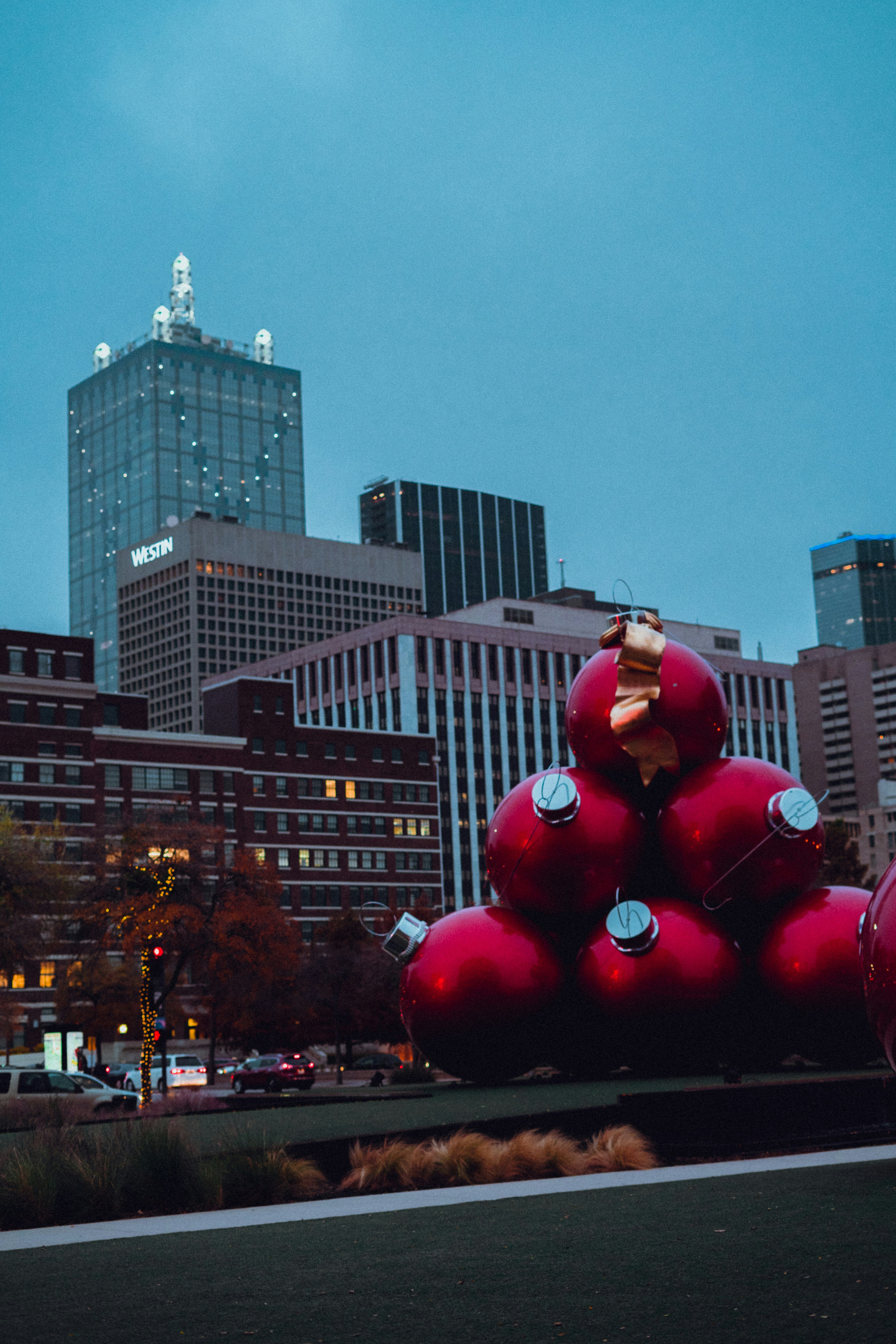 a large red balloon with a bow on top of it in front of a city