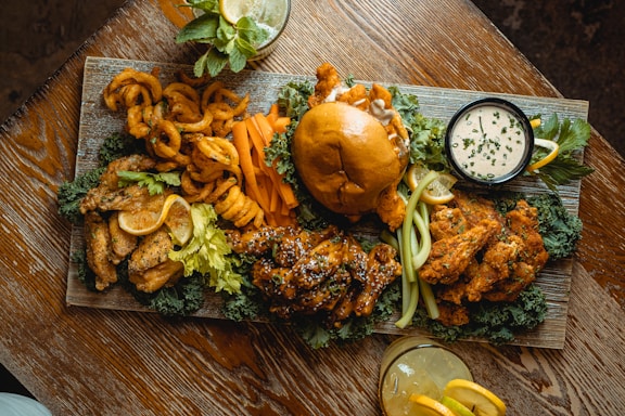 A rustic wooden table spread with crispy chicken wings, golden fries, and fresh coleslaw in vibrant bowls.