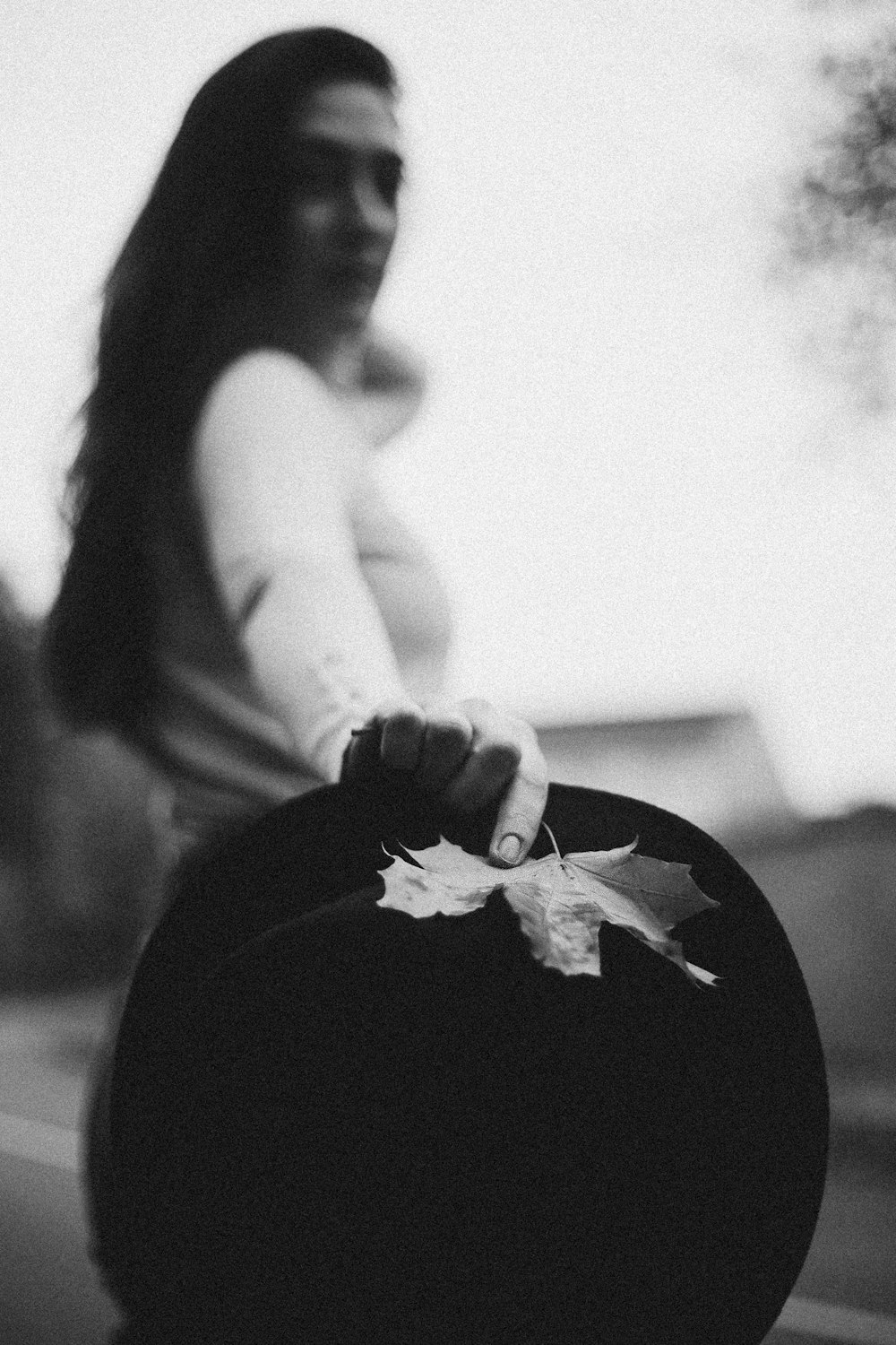 a woman holding a black hat with a leaf on it