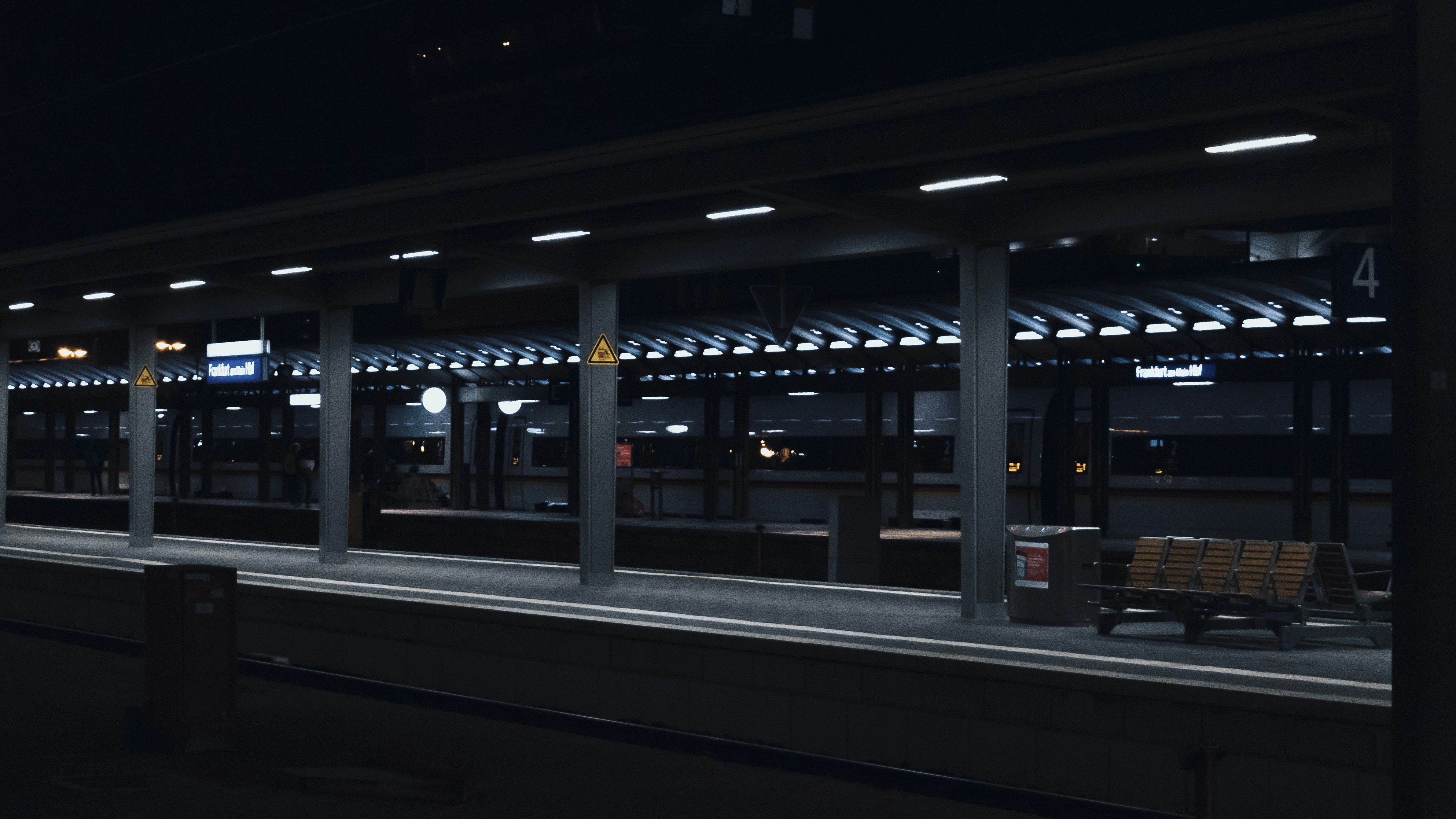 a train station at night with a bench in the foreground