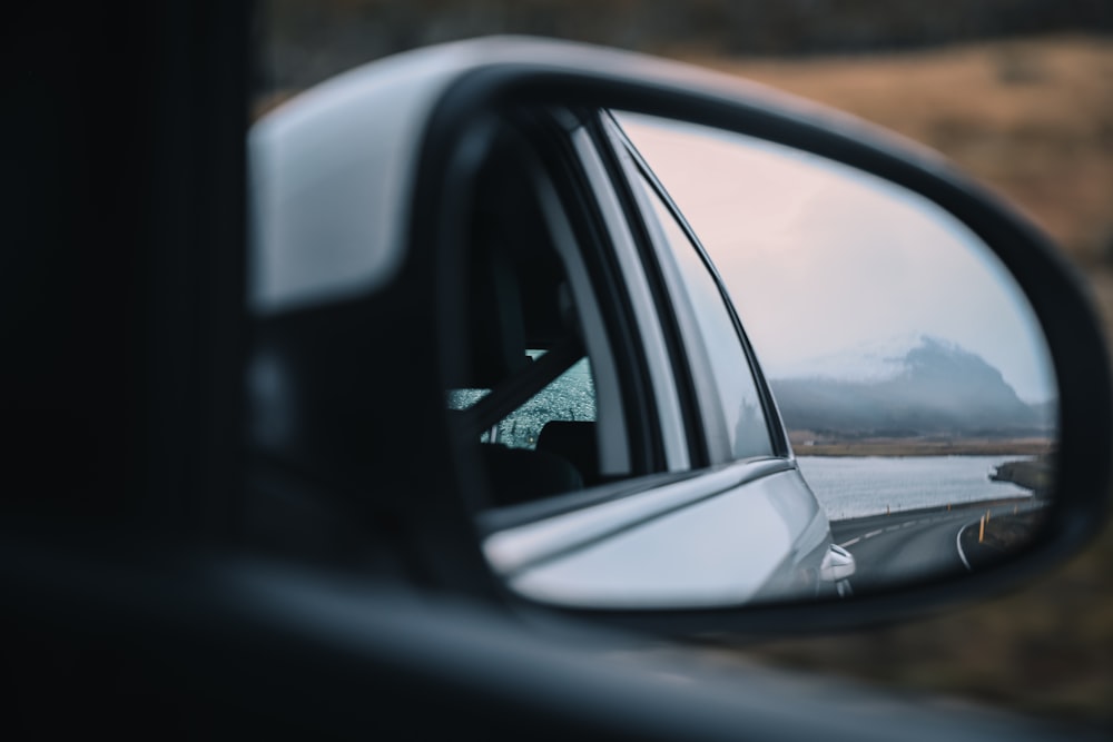 a car's side view mirror with a mountain in the background