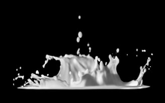 Dynamic, splashing liquid with droplets suspended mid-air, against a dark background.