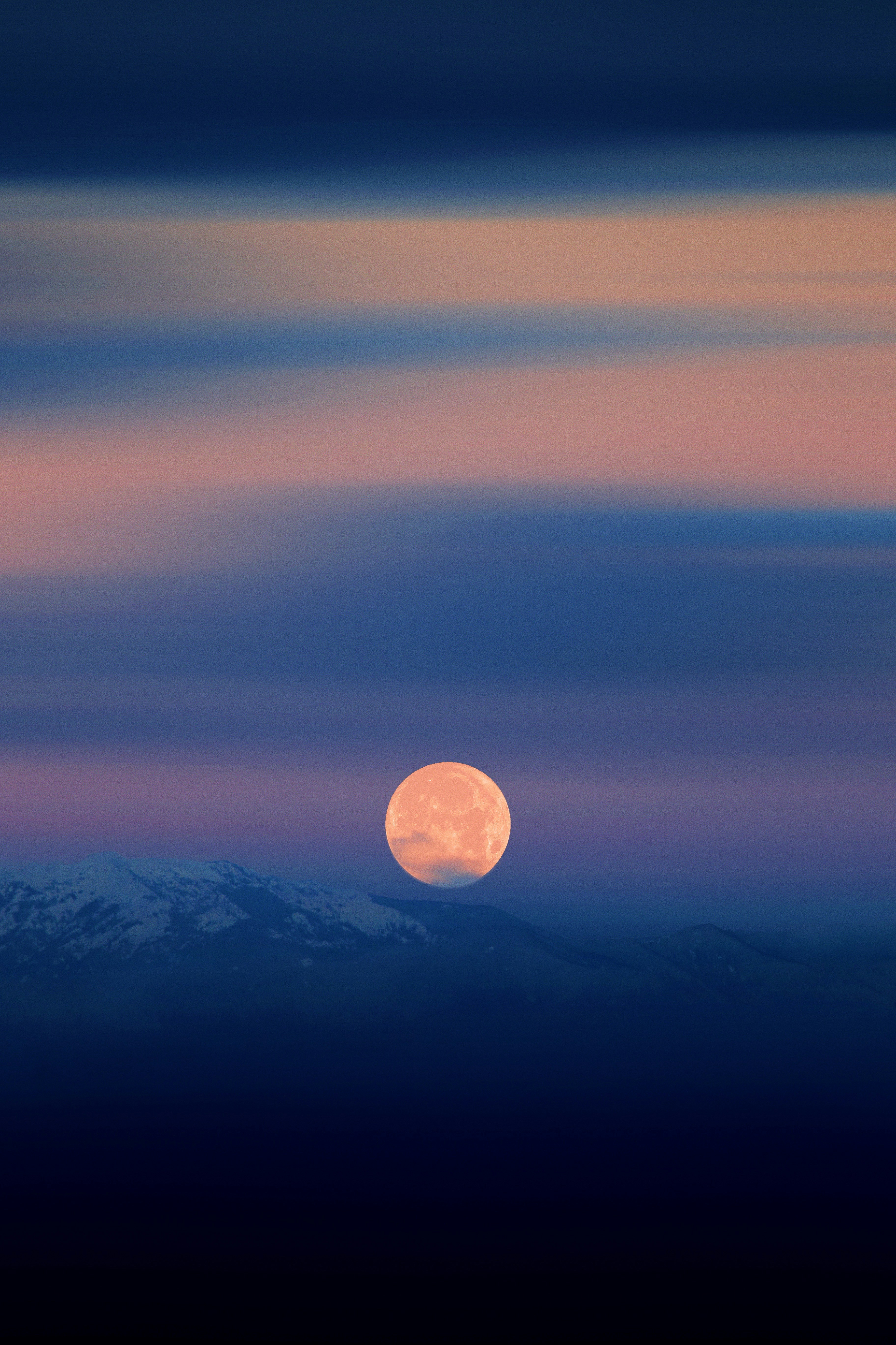 a full moon rising over a mountain range