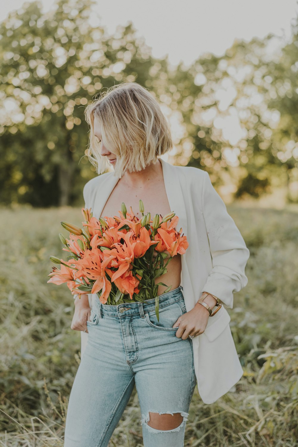 a woman in ripped jeans holding a bouquet of flowers