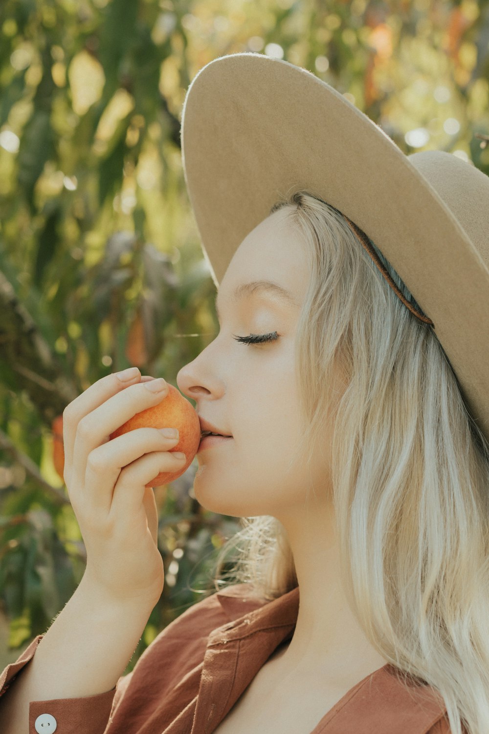 a woman in a hat is eating an apple