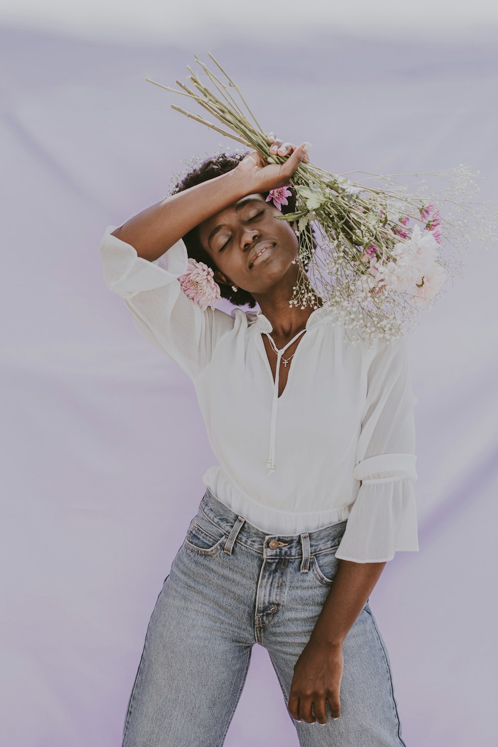 a woman holding a bunch of flowers on her head