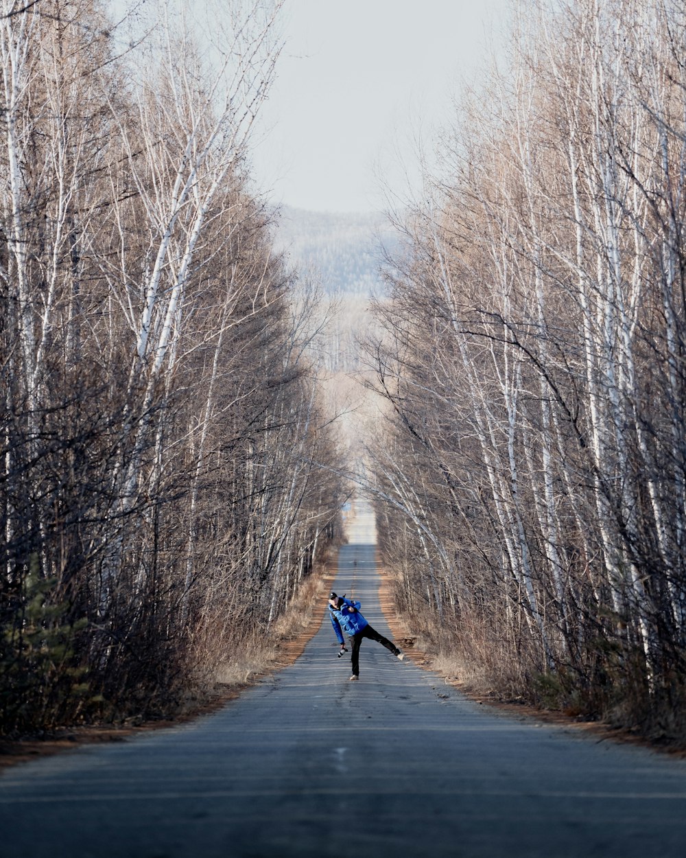 a person standing in the middle of a road surrounded by trees