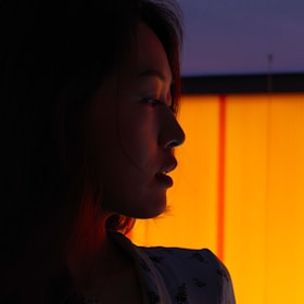 A playful silhouette of a woman laughing, framed by soft charcoal shadows and warm golden light.