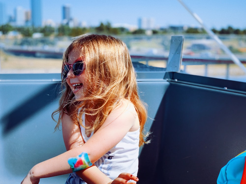 a little girl sitting on the back of a boat