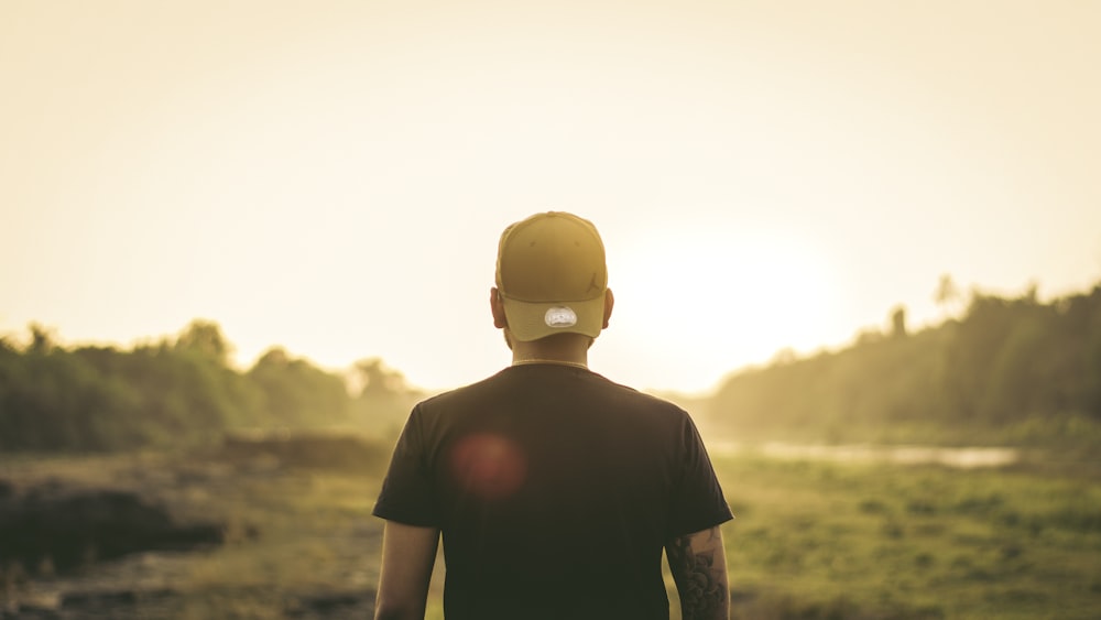 a man standing in a field with the sun behind him