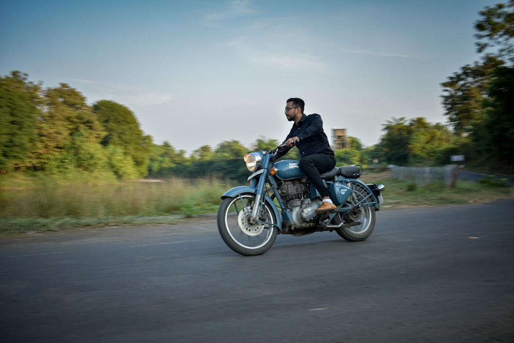 a man riding a blue motorcycle down a street