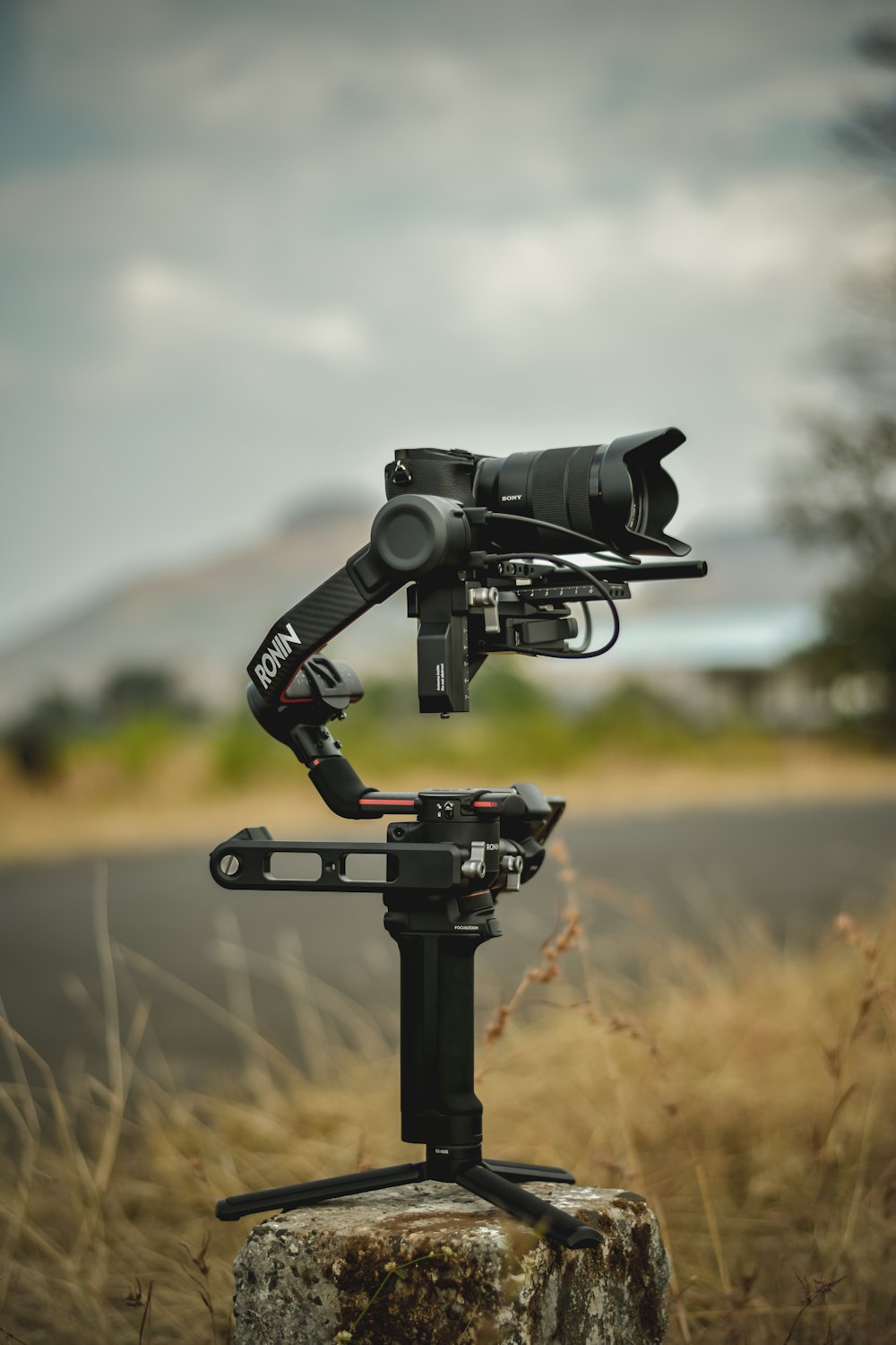 uma câmera conectada a um tripé em um campo