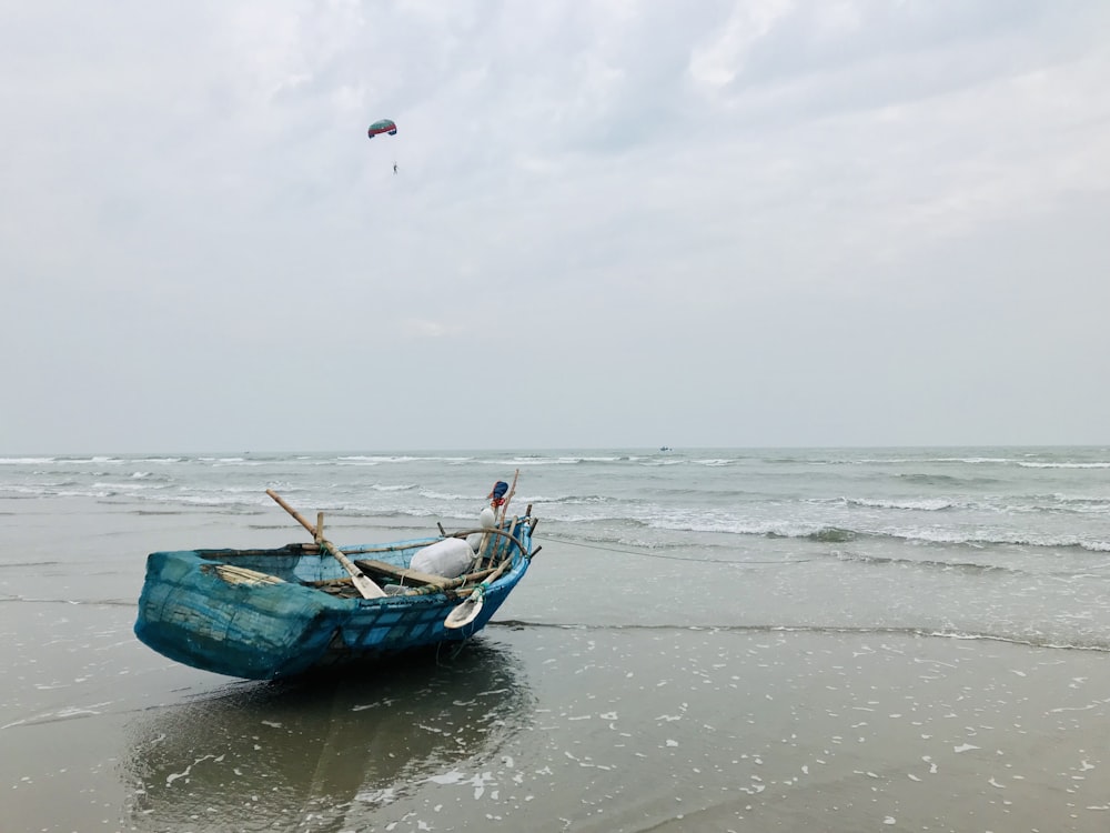 a blue boat sitting on top of a sandy beach