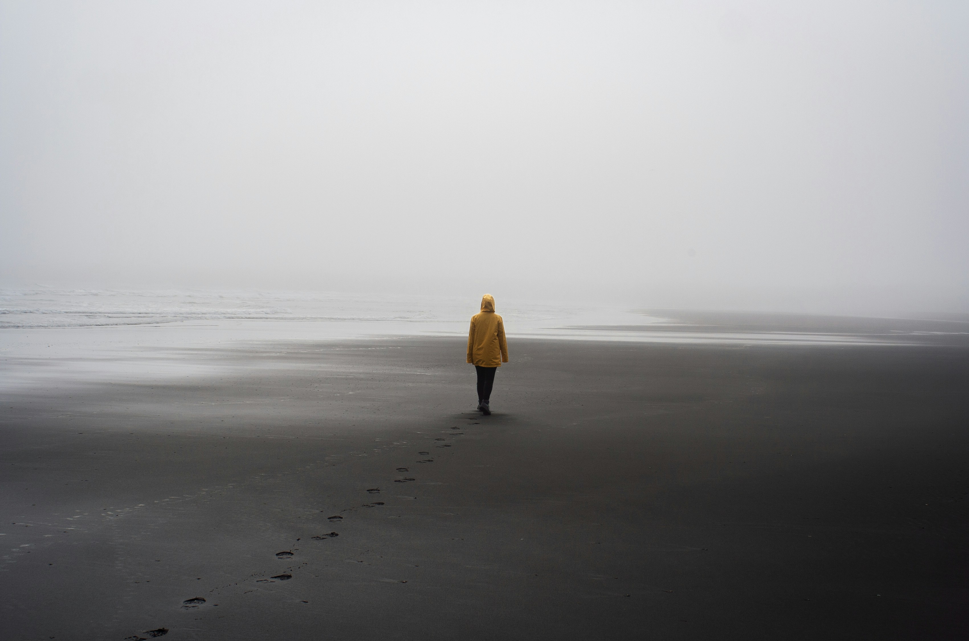 a person in a yellow jacket walking on a beach