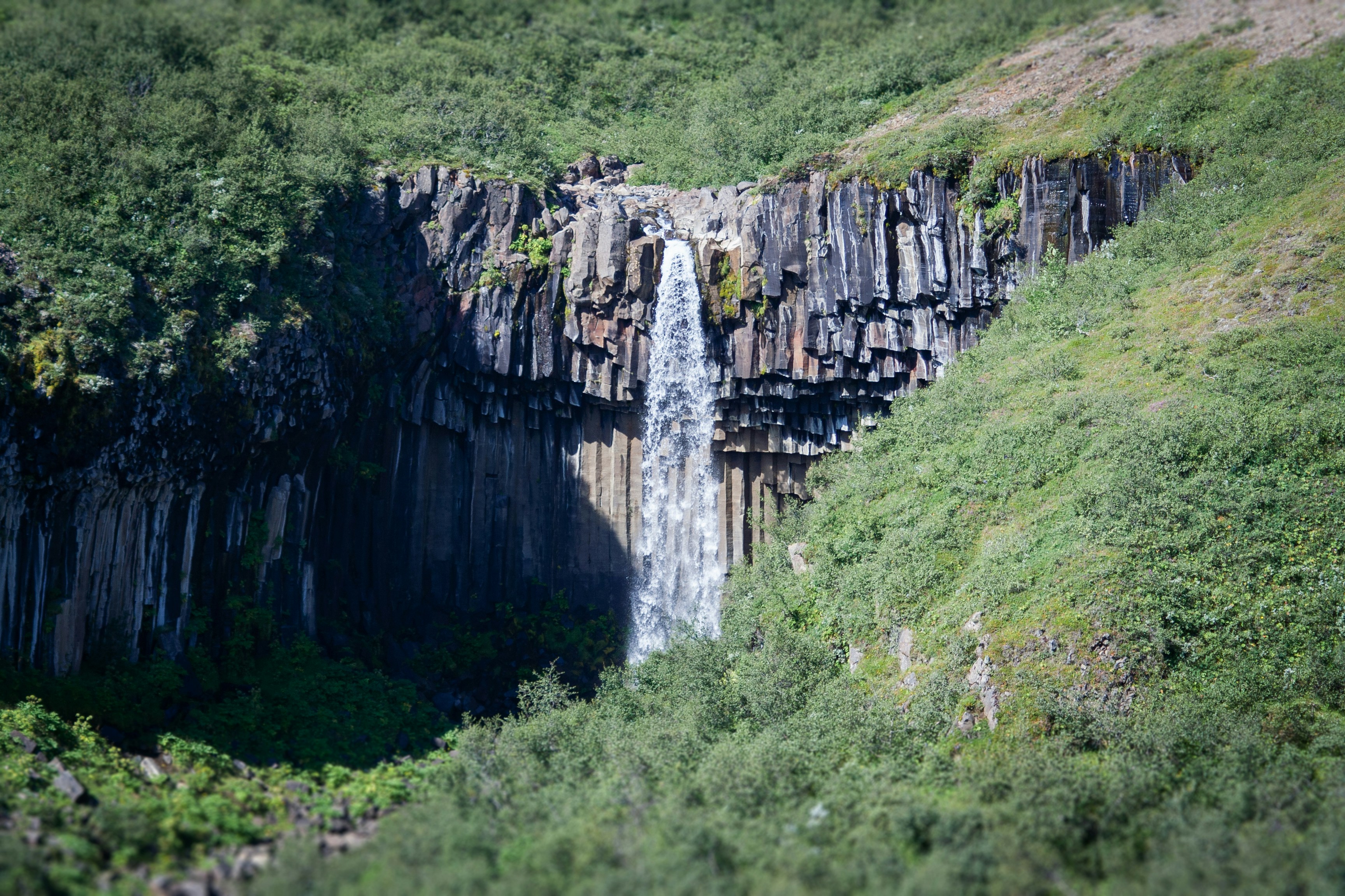 a very tall waterfall in the middle of a lush green forest