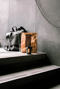 A stylish leather backpack placed on a café table next to a steaming cup of coffee and a notebook.