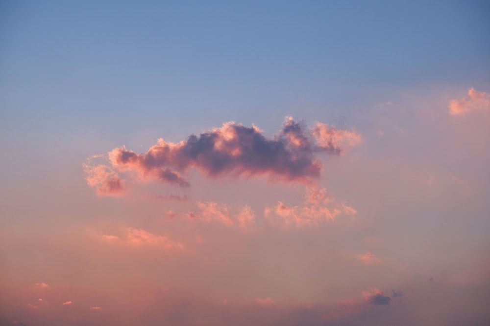 a pink cloud in a blue sky at sunset