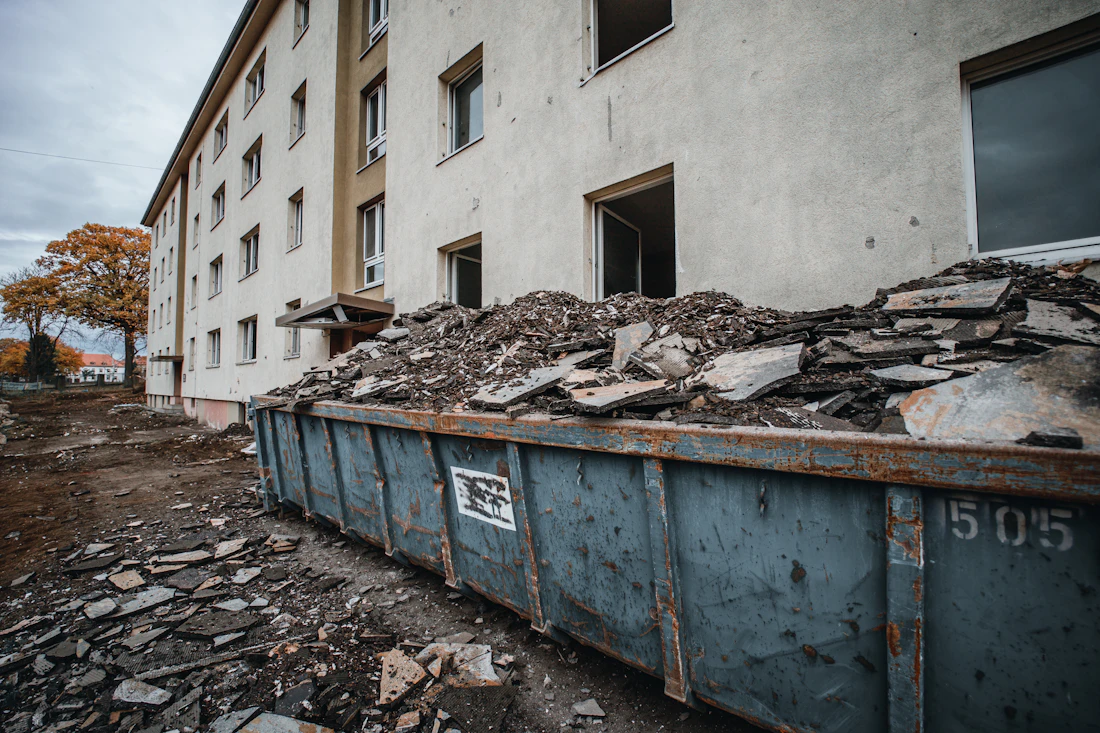 Container mit Rückbaumaterial vor einem Gebäude