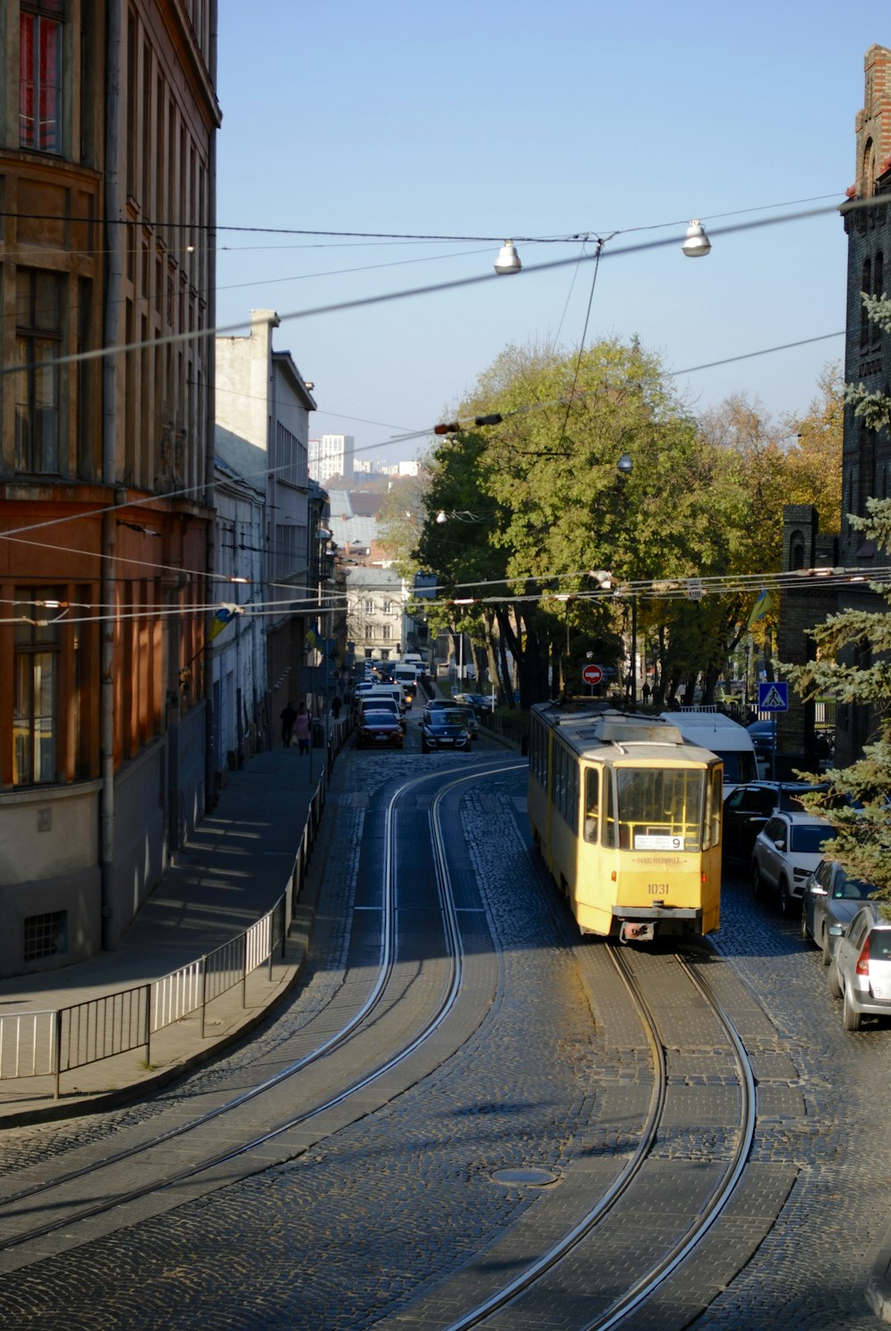 a yellow trolley is going down the tracks