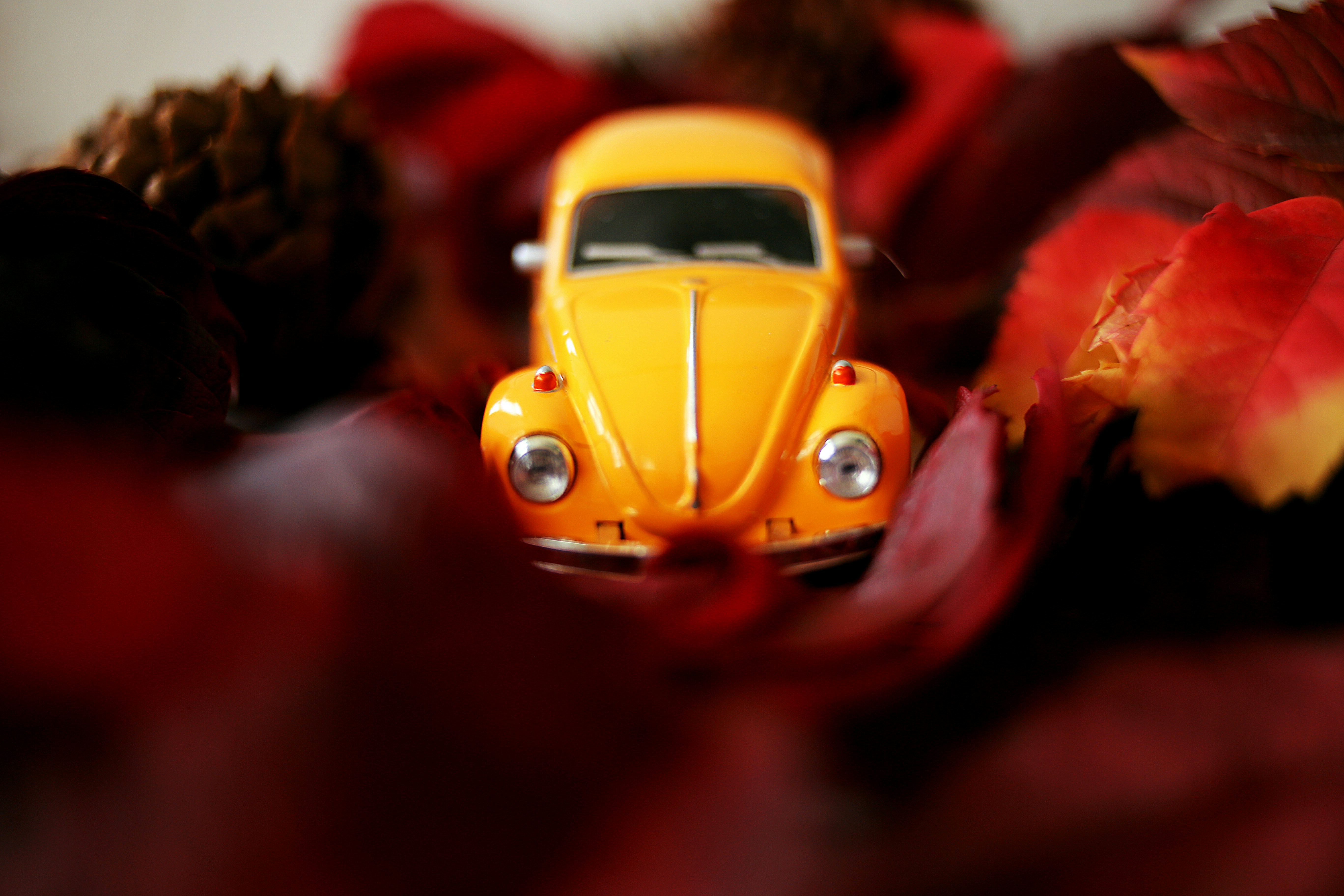 a yellow toy car sitting on top of a pile of leaves
