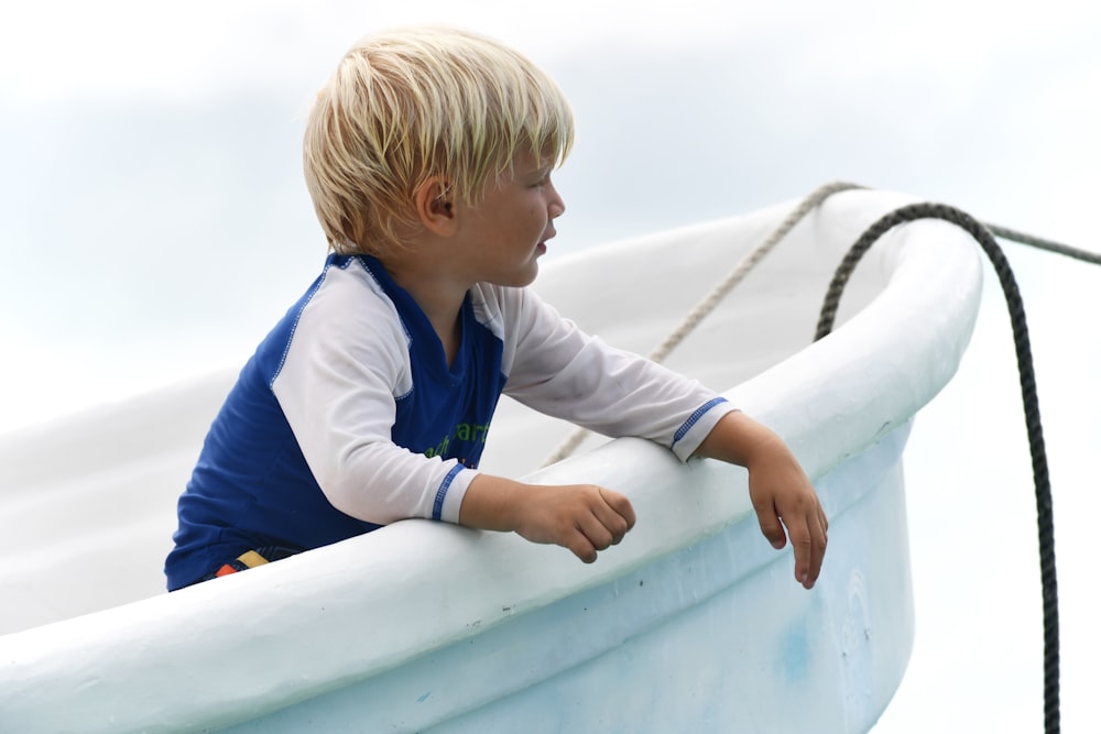 a little boy sitting in a boat on the water