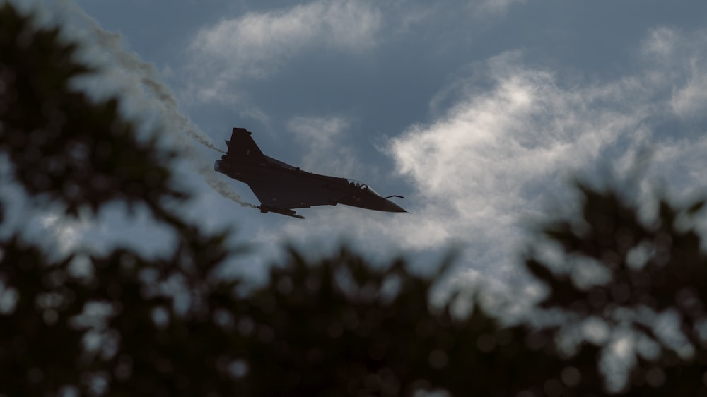 a fighter jet flying through a cloudy sky