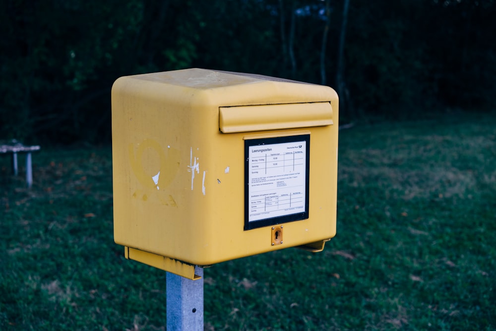 uma caixa amarela sentada em cima de um poste de metal