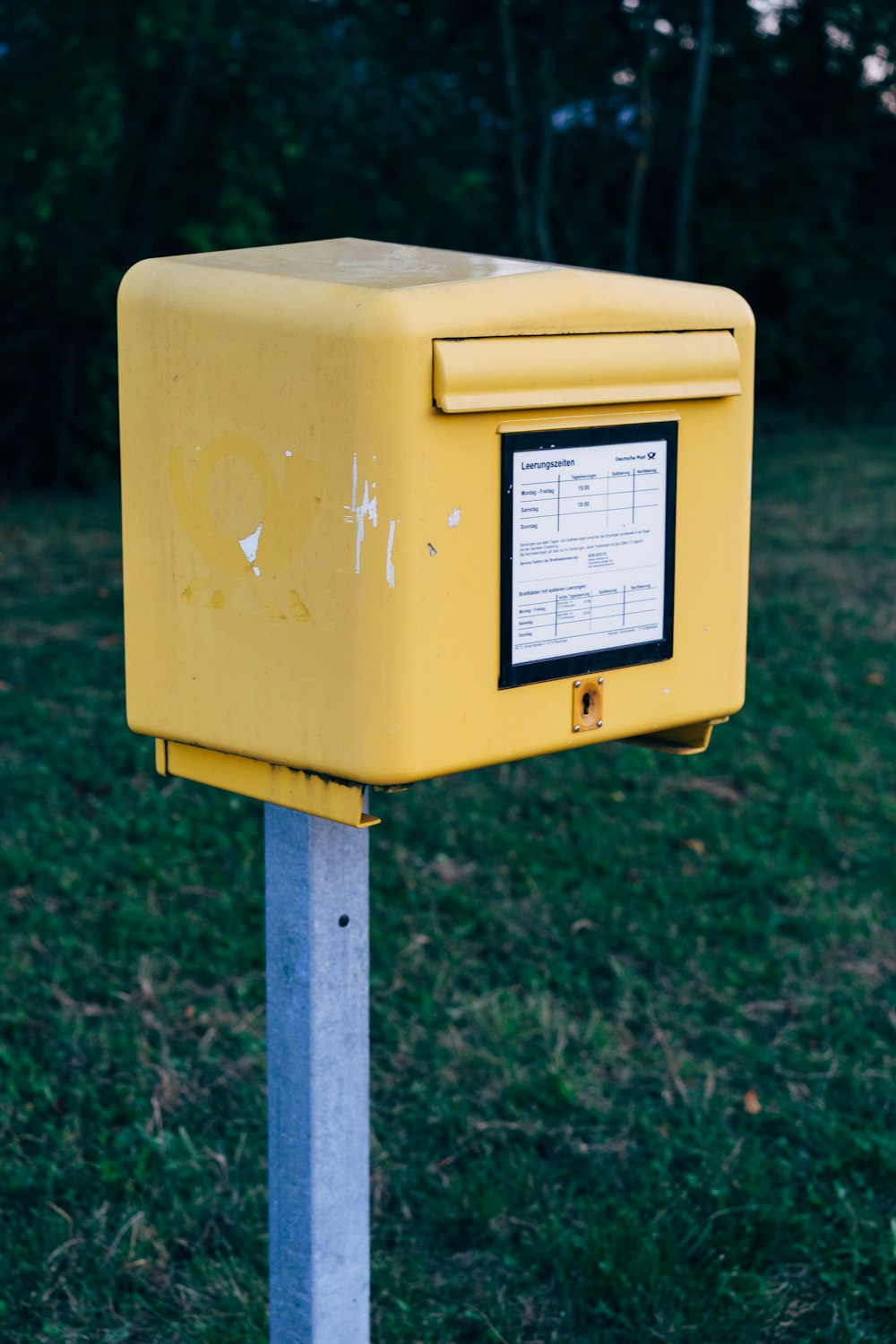 uma caixa de correio amarela sentada em cima de um poste de metal