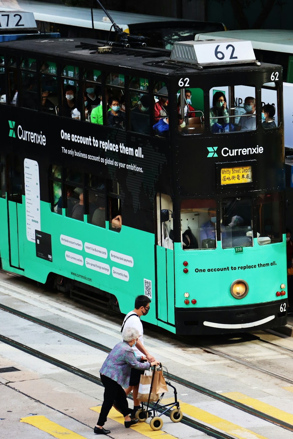 a person pushing a cart down a street in front of a bus