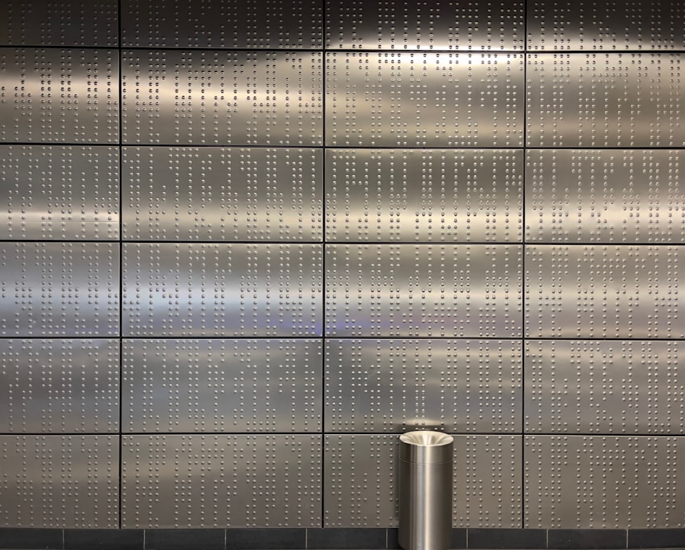 a metal wall with a trash can in front of it