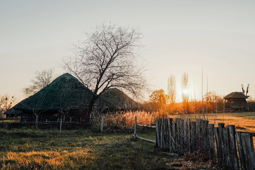 o sol está se pondo atrás de uma pequena cabana